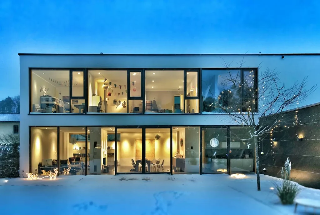 Featured project: a two-storey modern custom home with full-height windows, lit at dusk