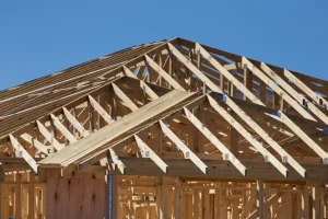 Home addition: new timber roof framing against a clear blue sky