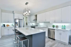 Kitchen renovation: white shaker cabinets, a dark island with a marble top and pendant lights