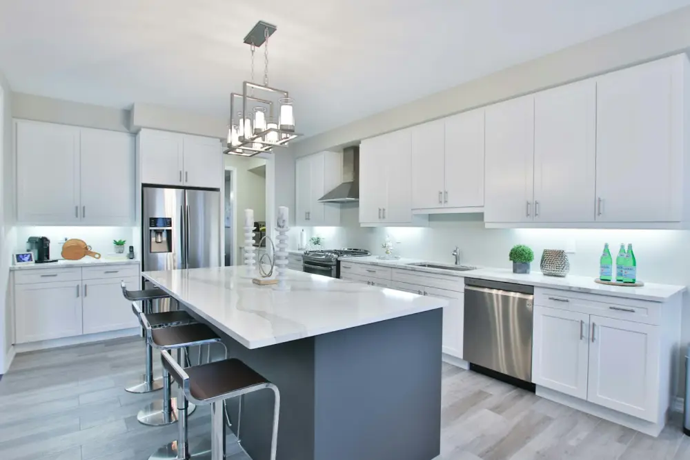 Kitchen renovation: white shaker cabinets, a dark island with a marble top and pendant lights
